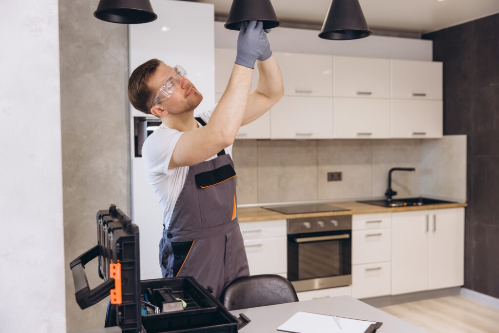 Electrician Installing Hanging Lamps in Modern Kitchen